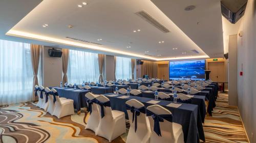 a conference room with blue tables and white chairs at Weilai J Hotel Kunming New Luoshuiwan Branch in Kunming