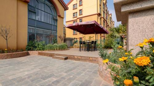 a patio with a table with an umbrella and flowers at Weilai J Hotel Kunming New Luoshuiwan Branch in Kunming