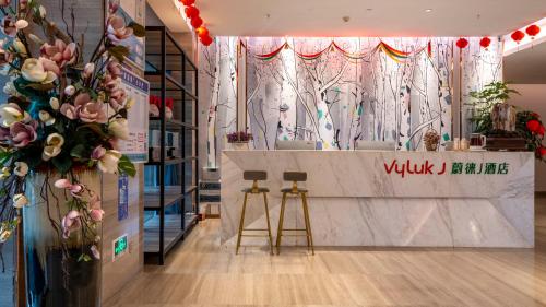 a store with two stools and a counter with flowers at Weilai J Hotel Kunming New Luoshuiwan Branch in Kunming