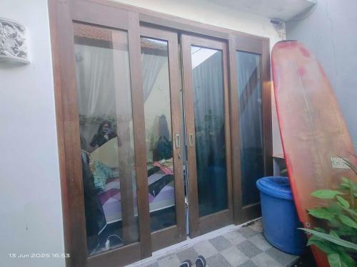 a room with a glass cabinet with a surfboard in it at Ubung Little House Denpasar in Sempidi