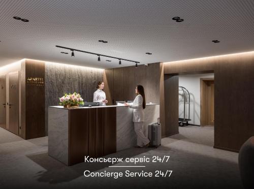 two women standing at a counter in a lobby at Apartel Uzhhorod in Uzhhorod