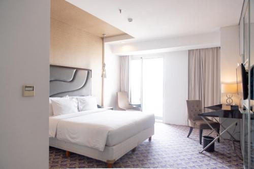 a hotel room with a bed and a desk at Nemuru Grand Bellevue Radio Dalam in Jakarta