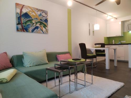 a living room with a green couch and a table at Haus Obermaiselstein in Obermaiselstein