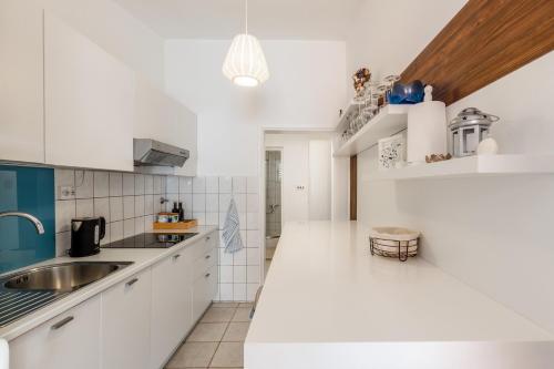 een witte keuken met witte kasten en een spoelbak bij Apartment Siranovic in Batalaži