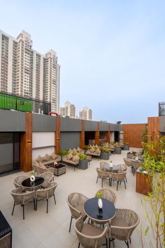 a rooftop patio with tables and chairs and buildings at Saltstayz Autograph - Advant & Sector 144 in Noida