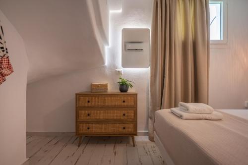 a bedroom with a bed and a dresser and a window at Depis private villas Plaka Naxos in Plaka