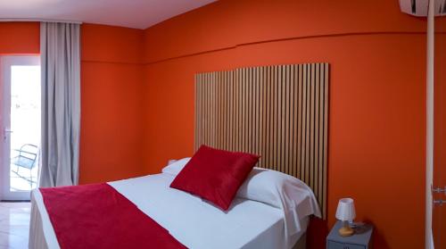 a bedroom with orange walls and a bed with a red pillow at Davila Flat Hotel in Fortaleza