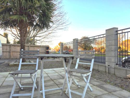 a table and two chairs sitting next to a fence at Highway to Hobbiton Guesthouse - Matamata Central Location in Matamata