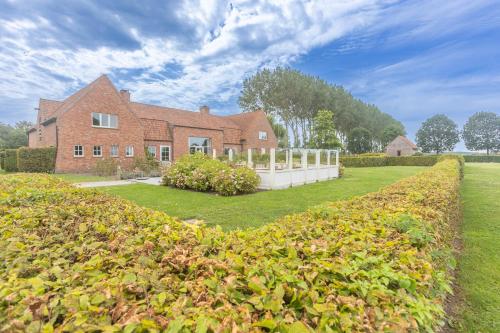 a brick house with a hedge in front of it at HuysHoeve in Knokke-Heist