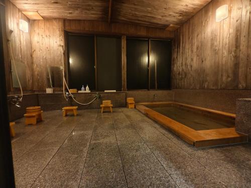 an empty room with a bath tub and benches at 旅館青柳 海越し立山連峰の雪山絶景で休もう in Himi
