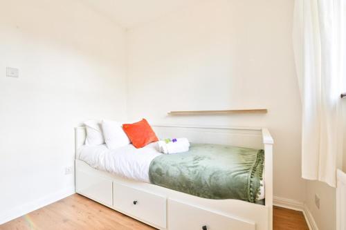 a white bedroom with a bed with white sheets and orange pillows at Homely 5 Bed House - 15 Mins to Cardiff City in Cardiff