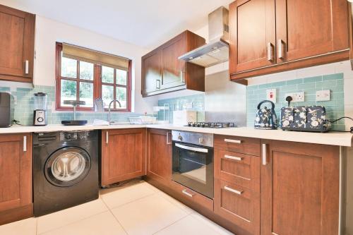 une cuisine avec des armoires en bois et une laveuse et une sécheuse dans l'établissement Homely 5 Bed House - 15 Mins to Cardiff City, à Cardiff
