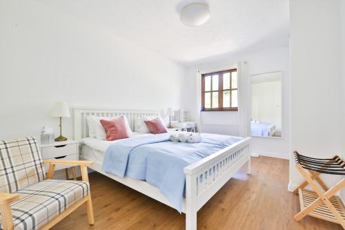 a white bedroom with a white bed and a chair at Homely 5 Bed House - 15 Mins to Cardiff City in Cardiff