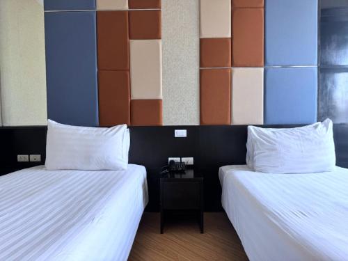 two beds sitting next to each other in a room at The Sunreno Hotel Bangkok in Bangkok