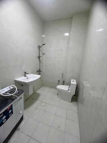 a white bathroom with a sink and a toilet at Red 8 - OKAAD in Salalah