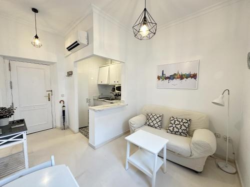 biały salon z kanapą i stołem w obiekcie Encantador apartamento en el centro de Sevilla w Sewilli