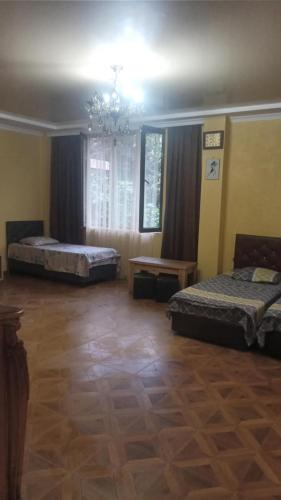 a bedroom with two beds and a chandelier at ბიჭვნარის სახლი in Itʼkhvisi