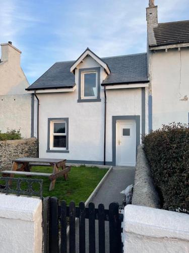 a white house with a picnic table in front of it at Fernbank Cottage - Bruichladdich, Isle of Islay in Bruichladdich
