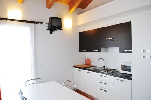 a kitchen with white cabinets and a tv on the wall at Hotel Helga in Caorle