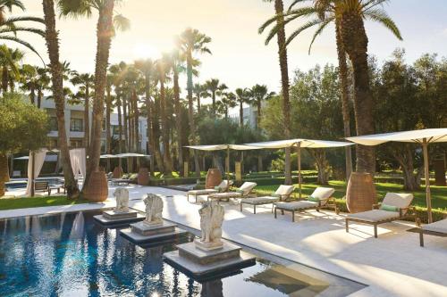 a pool with chairs and umbrellas and palm trees at The Ritz-Carlton Rabat, Dar Es Salam in Rabat