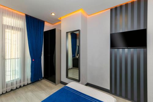 a bedroom with a bed and a tv and a mirror at The Great Airport Hotel in Arnavutköy