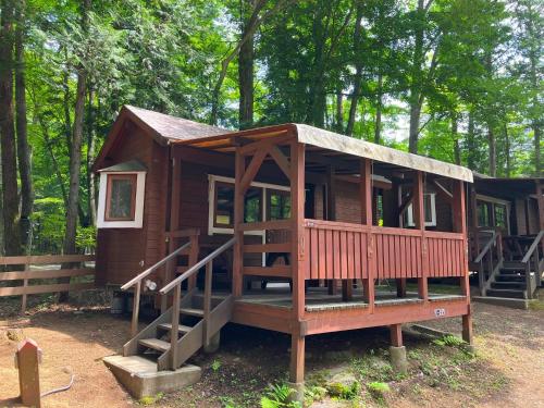 a small wooden cabin in the woods with stairs at PICA Fujiyoshida in Fujiyoshida