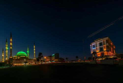 a building with a mosque with a green dome at night at The Great Airport Hotel in Arnavutköy