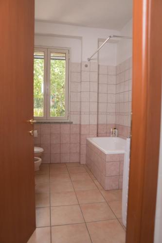 a bathroom with a tub and a toilet and a sink at Casa Lumiere in Iglesias