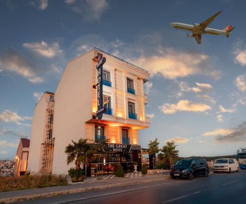 an airplane is flying over a building with a hotel at The Great Airport Hotel in Arnavutköy