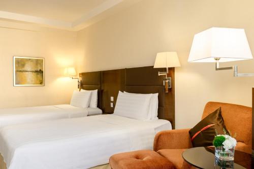 a hotel room with two beds and a chair at Shangri-La Shenzhen - Nearby Luohu Border, Outdoor Swimming Pool in Shenzhen