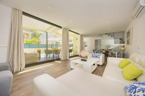 a living room with white furniture and a large window at Villa Jade I in Can Picafort