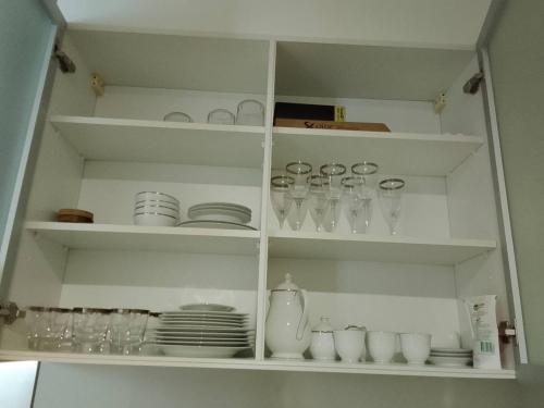 a white cabinet filled with glasses and plates and dishes at Veranda Residence Pattaya By Suia in Na Jomtien