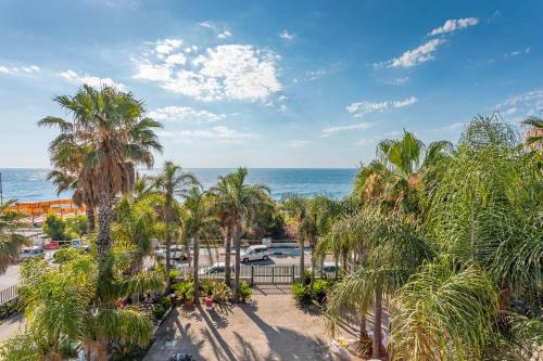 an aerial view of a resort with palm trees and the ocean at I Ciottoli Dello Ionio in Mascali
