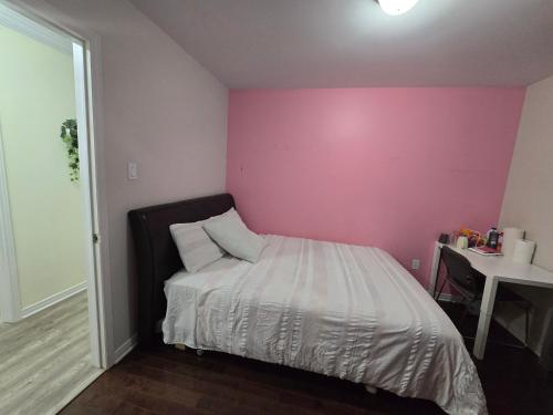 a bed in a room with a pink wall at Cozy Room 4mins from Ottawa-Gatineau Airport in Gatineau