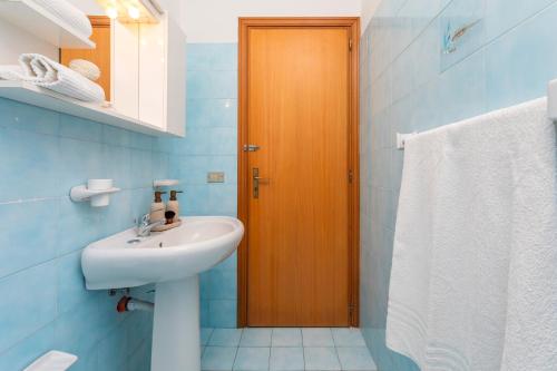 a bathroom with a sink and a wooden door at I Ciottoli Dello Ionio in Mascali