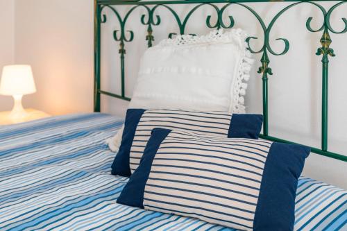 a bed with a blue and white striped comforter at I Ciottoli Dello Ionio in Mascali