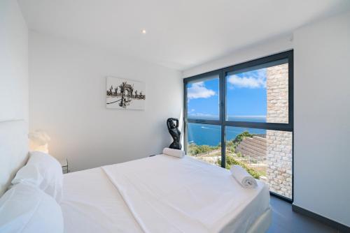 une chambre avec un lit et une grande fenêtre dans l'établissement Duplex - Terrasse vue mer & Jacuzzi - Parking - DU, à Èze