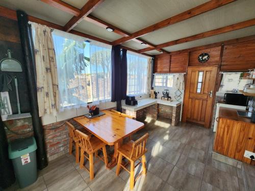 una sala da pranzo con tavolo in legno e alcune finestre di Addo Bush & Bay Cottage a Gqeberha