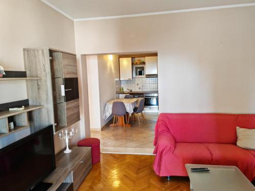 a living room with a red couch and a kitchen at Apartmani CVJET in Makarska