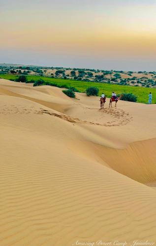 two people riding horses on the sand in the desert at Amazing Desert Camp in Jaisalmer