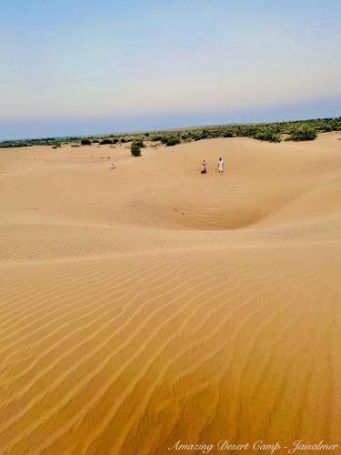 two people walking in the sand in the desert at Amazing Desert Camp in Jaisalmer