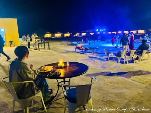 a woman sitting at a table in front of a stage at Amazing Desert Camp in Jaisalmer