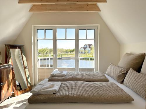 ノイハルリンガージールにあるFischerhäuschen am Kurpark-See ohne Schwimmbad- und Saunanutzungの大きな窓のある部屋にベッドが2つある