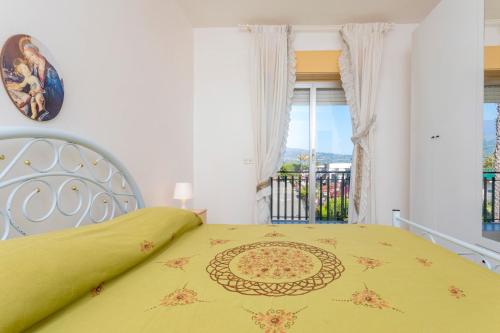 a bedroom with a yellow bed and a balcony at I Ciottoli Dello Ionio in Mascali