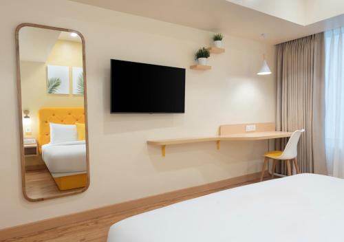 a hotel room with a bed and a mirror at Bloom Hotel - DLF Road Gachibowli in Kondapur
