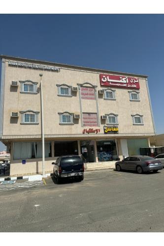 a large building with cars parked in front of it at نزل اكنان للشقق المخدومة in Najran