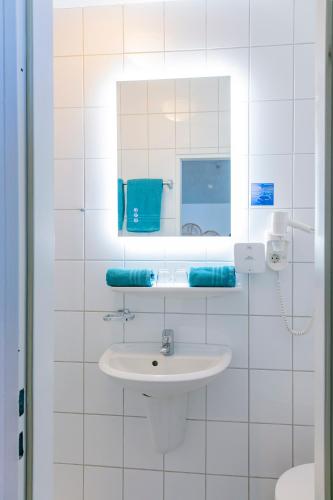 a white bathroom with a sink and a mirror at Hotel Bethanien in Langeoog
