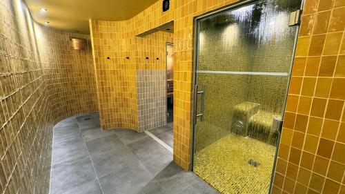 a bathroom with yellow tile walls and a walk in shower at Kyriad Prestige Compiègne Hotel & Spa in Compiègne