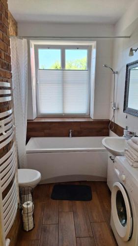 a bathroom with a tub and a sink and a window at Apartament VINCENT in Mrągowo