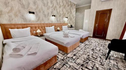 una camera d'albergo con due letti con asciugamani sopra di Maksima Hotel a Samarkand